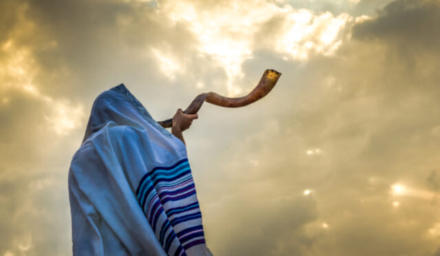 Jewish person in a tallit prayer shawl against dramatic sky